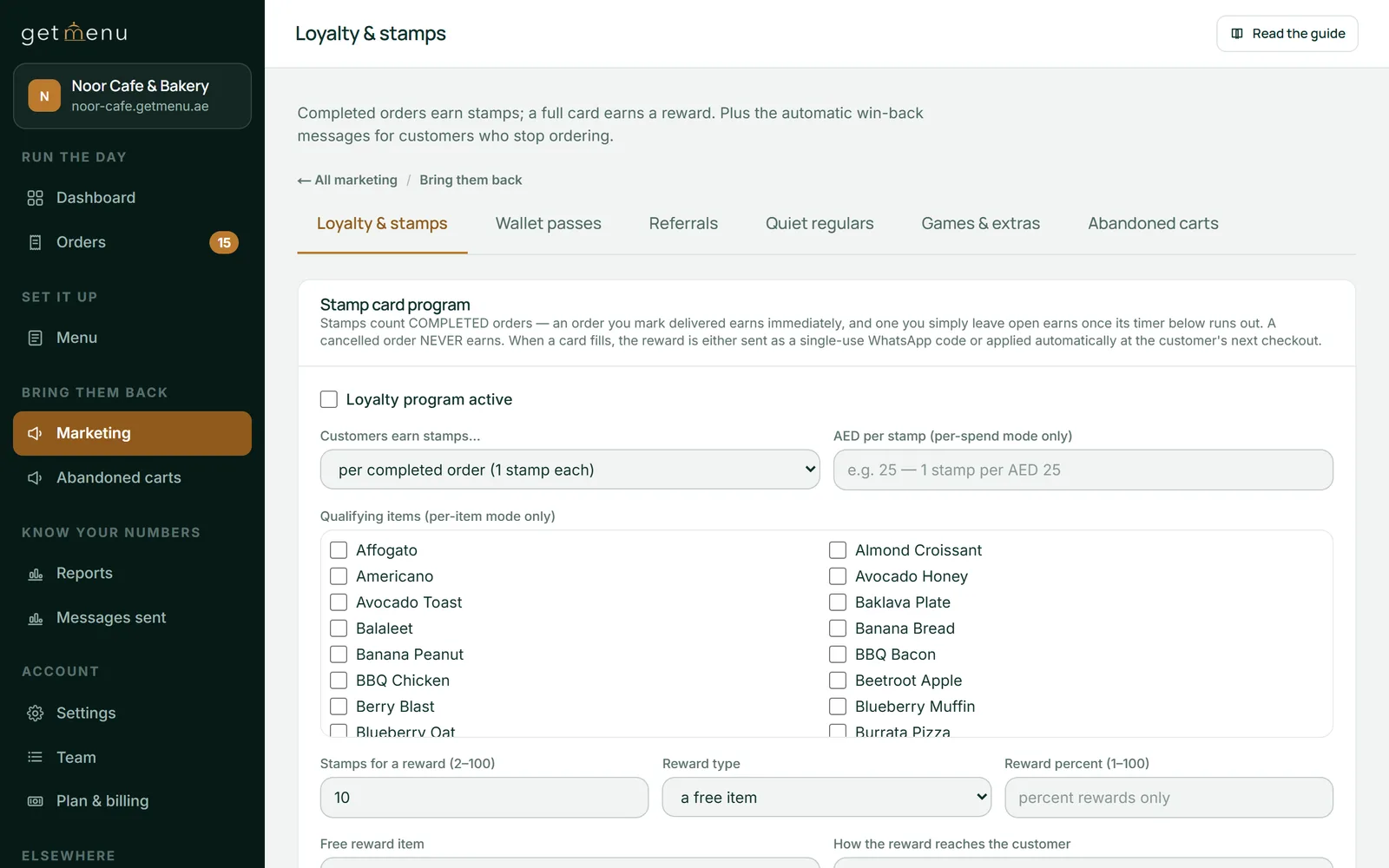 The Loyalty & stamps page of the GetMenu dashboard for the demo restaurant Noor Cafe & Bakery. Tabs read Loyalty & stamps, Wallet passes, Referrals, Quiet regulars, Games & extras and Abandoned carts. Below them is the Stamp card program form: an unticked Loyalty program active box, customers earn stamps per completed order, a list of menu items to tick for per-item stamps, 10 stamps for a reward, and a free item as the reward type.
